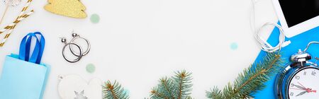 panoramic shot of digital tablet, fir branch, christmas baubles, alarm clock, earrings, gift bag, earphones isolated on whiteの写真素材