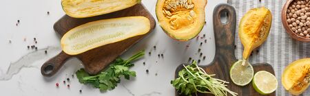 panoramic shot of zucchini, pumpkin and sprouts on wooden cutting boards on marble surface