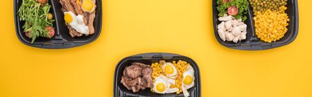 panoramic shot of eco packages with vegetables, meat, fried eggs and salads isolated on yellowの写真素材