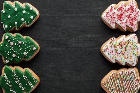 flat lay with delicious glazed Christmas tree cookies on black background with copy spaceの写真素材