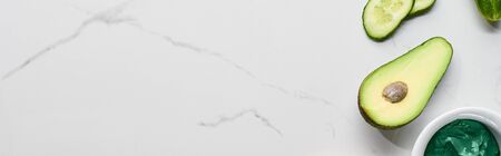 panoramic shot of green beauty product, avocado and cucumber on marble surface