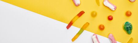 panoramic shot of colorful gummy sweets on yellow and white background, Halloween treatの写真素材