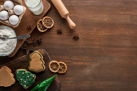 top view of delicious Christmas cookies near ingredients and spices on wooden tableの写真素材