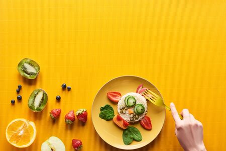 cropped view of woman eating fancy cow made of food on colorful orange backgroundの写真素材