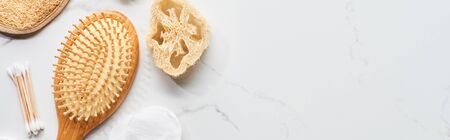 panoramic shot of cotton swabs, hair brush and loofah on marble surface