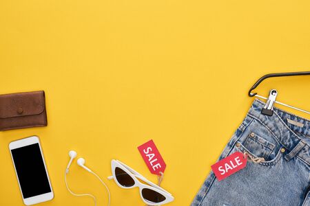 top view of fashionable clothing and accessories with smartphone and sale labels on yellow backgroundの写真素材