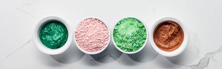 panoramic shot of cups with color beauty products on marble surfaceの写真素材