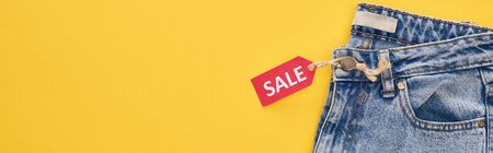 top view of jeans with sale label isolated on yellowの写真素材