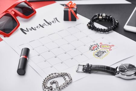 selective focus of calendar with lettering november, lipstick, gift, sunglasses, bracelets, wristwatchの写真素材