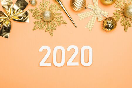 top view of 2020 numbers near golden christmas decoration on orange backgroundの写真素材