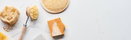 panoramic shot of face sponge, loofah, body brush and soap on marble surface