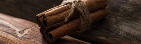 close up view of cinnamon sticks on wooden background, panoramic shot