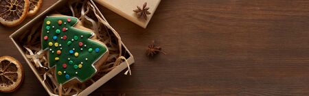 top view of Christmas tree cookie in box near dried citrus and anise at wooden table, panoramic shotの写真素材