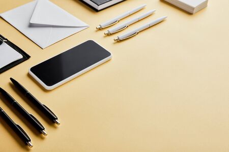 envelope, pens, business cards, smartphone with copy space on yellow background