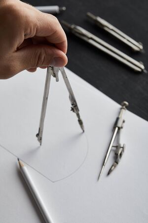 cropped view of man drawing circle on paper with compassの写真素材