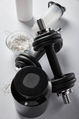 top view of sports bottle near bowl with protein powder and dumbbells on whiteの写真素材