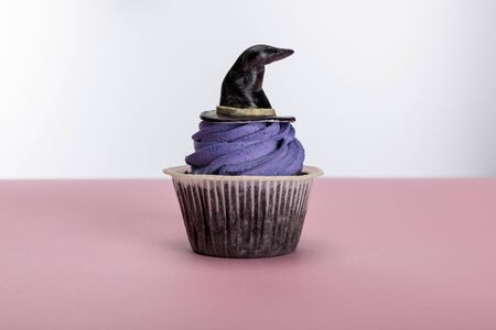 delicious Halloween cupcake with purple cream and hat on pink surface isolated on whiteの写真素材