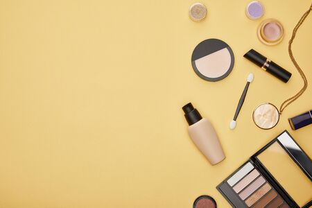 top view of face foundation and eye shadow isolated on yellowの写真素材