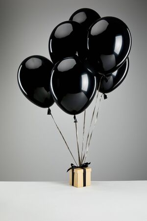 bunch of black balloons with gift box isolated on grey, black Friday conceptの写真素材