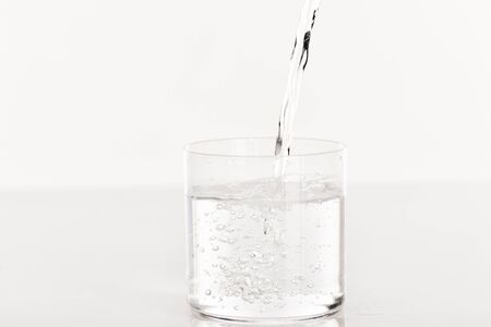 clear fresh water pouring into glass isolated on white