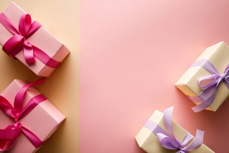 top view of gift boxes with ribbons on pink and beige background