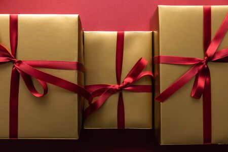 flat lay with golden gift boxes with ribbons on red background