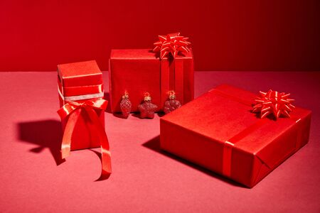 red wrapped festive gift boxes with ribbons and bows on red backgroundの写真素材