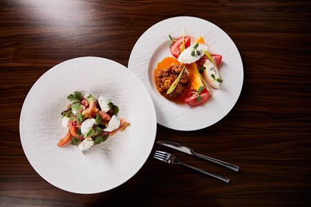 top view of delicious restaurant dish with eggplant caviar and tomatoes and salad on wooden table...
