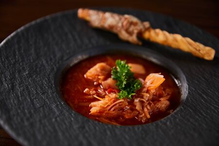 close up view of traditional ukrainian borscht garnished with parsley in black plateの写真素材