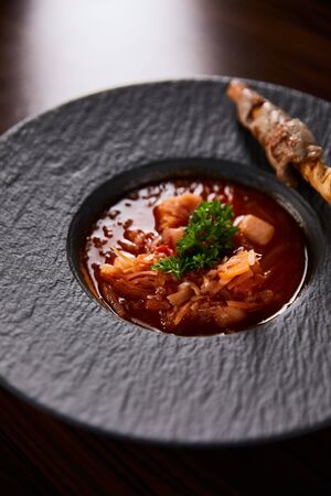 traditional ukrainian borscht garnished with parsley in black plate