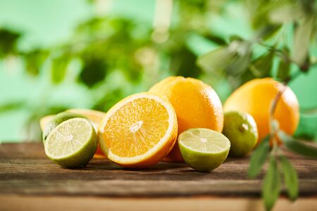 selective focus of cut, whole oranges and limes on wooden surfaceの写真素材