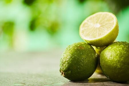 selective focus of whole and cut limes with drops on marble surface