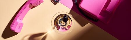 Top view of martini in glass with pink telephone on colorful background, panoramic shotの写真素材
