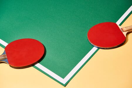 Two table tennis rackets on yellow and green surface