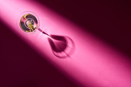 Top view of martini with olive on pink background with shadowの写真素材