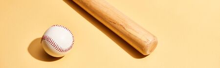 Baseball bat and ball on yellow background, panoramic shot