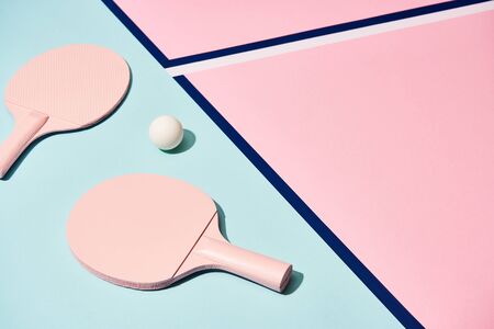 High angle view of ping pong rackets and ball on pastel surface with blue linesの写真素材