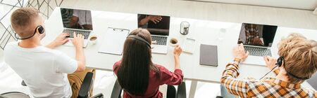 panoramic shot of brokers in headsets working in call center