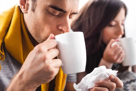 selective focus of sick boyfriend drinking tea and holding napkinの写真素材
