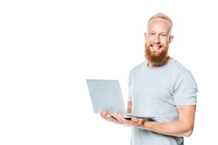cheerful bearded man holding laptop, isolated on whiteの写真素材