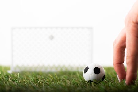 cropped view of female fingers near toy football gates and ball on green field isolated on white, sports betting conceptの写真素材