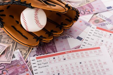 baseball glove and ball near betting lists on euro and dollar banknotes, sports betting conceptの写真素材