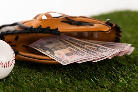 selective focus of dollar banknotes in baseball glove on green grass isolated on white, sports...