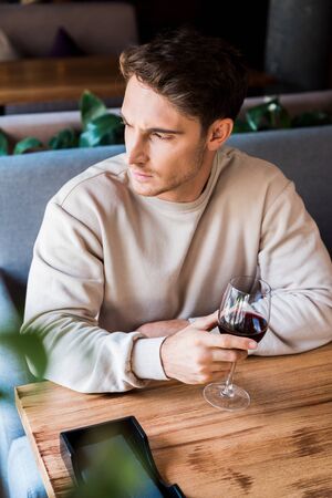 selective focus of man holding glass with red wine in restaurant