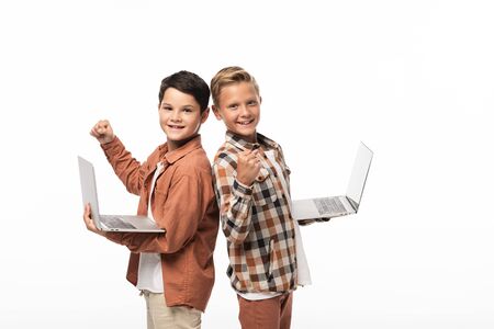 two smiling brothers holding laptops, showing thumbs up and looking at camera isolated on whiteの写真素材