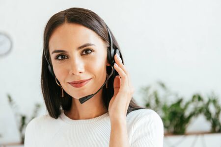 happy broker in headset looking at camera in office