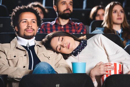 selective focus of woman sleeping on shoulder of her african american friend in cinema