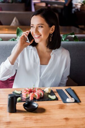 happy woman talking on smartphone in sushi barの写真素材