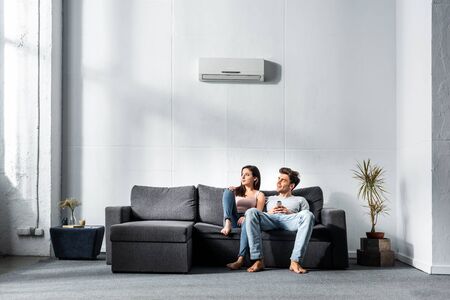 attractive girlfriend and handsome boyfriend sitting on sofa in apartmentの写真素材