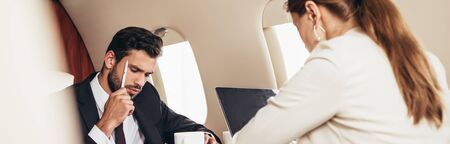 panoramic shot of pensive businessman in suit in private plane